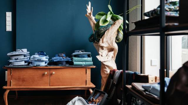 Innenaufnahme eines stilvollen Herrenausstatters: Auf einem Holzsideboard liegen gefaltete Hemden, daneben steht eine dekorative Holzskulptur mit Orchidee.